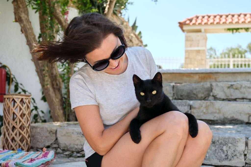 Happy woman with black cat, outdoor portrait of owner and pet